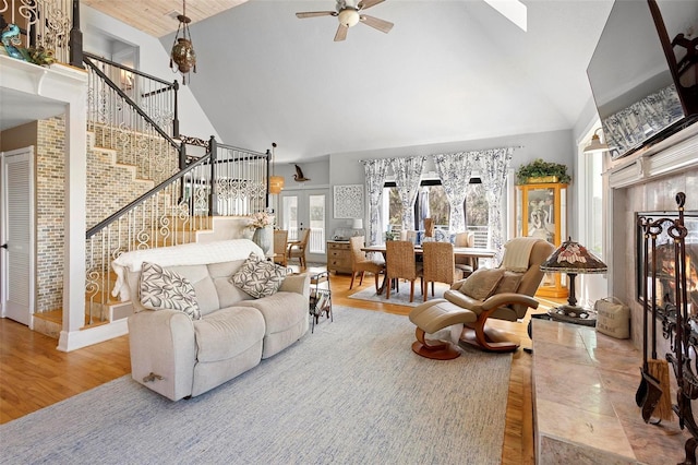 living room with french doors, high vaulted ceiling, ceiling fan, a premium fireplace, and hardwood / wood-style floors