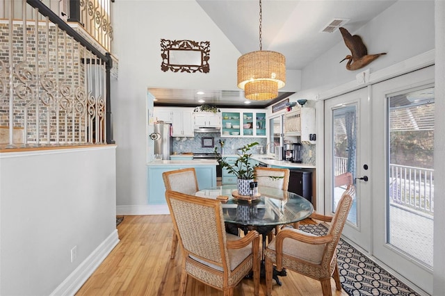 dining space with vaulted ceiling, sink, light hardwood / wood-style flooring, and french doors