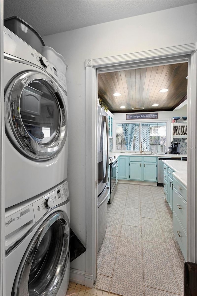 laundry area with stacked washing maching and dryer, sink, a textured ceiling, and wooden ceiling