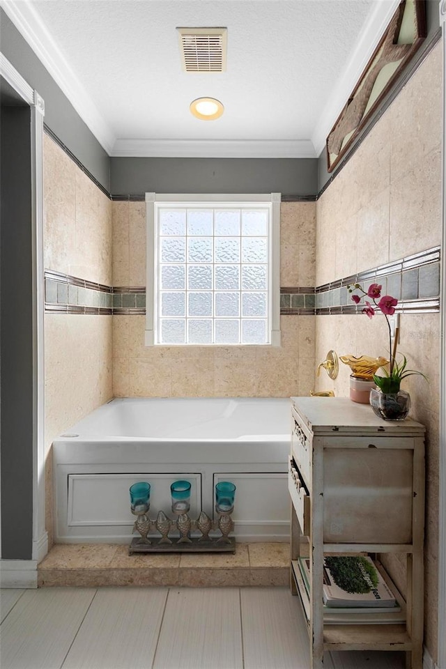 bathroom with crown molding, a tub to relax in, and tile walls