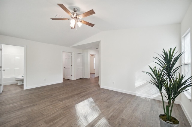 unfurnished bedroom with ensuite bathroom, ceiling fan, vaulted ceiling, and dark wood-type flooring