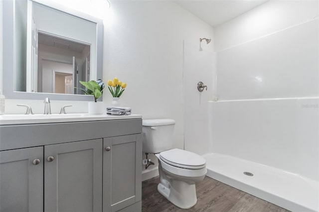 bathroom with a shower, vanity, toilet, and hardwood / wood-style floors