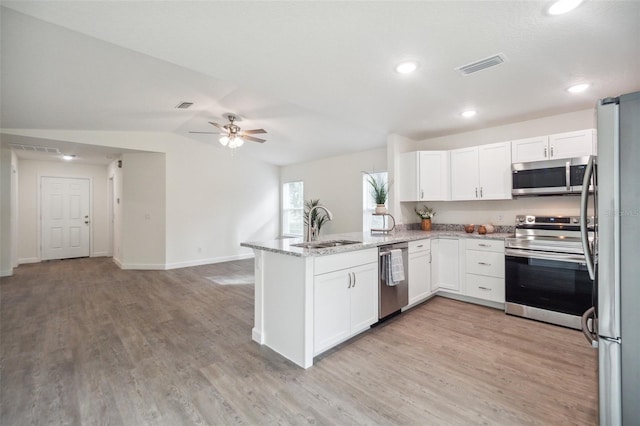 kitchen featuring appliances with stainless steel finishes, white cabinets, light hardwood / wood-style floors, sink, and kitchen peninsula