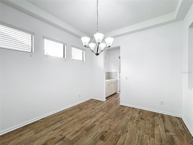 unfurnished room featuring an inviting chandelier and dark hardwood / wood-style flooring