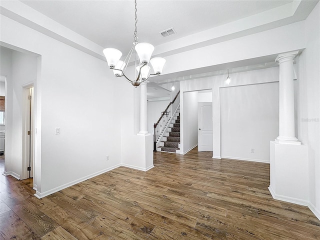 unfurnished dining area featuring ornate columns, a chandelier, and dark hardwood / wood-style flooring