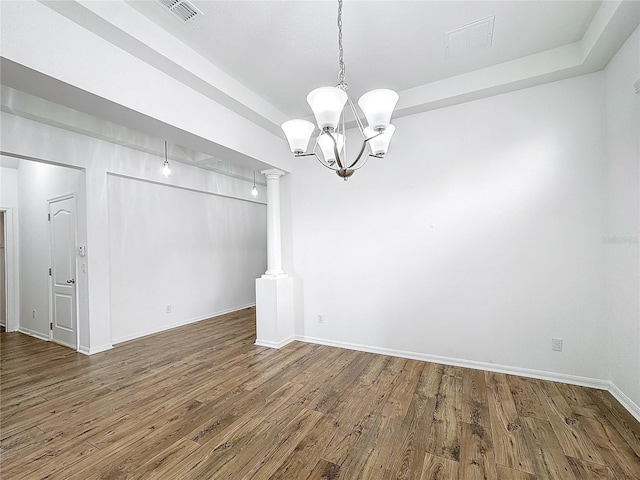 unfurnished dining area with a notable chandelier, hardwood / wood-style floors, and ornate columns