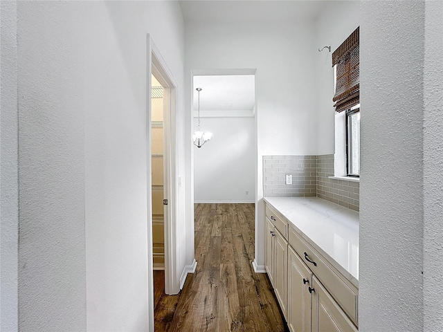 corridor featuring dark wood-type flooring and a chandelier