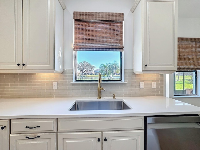 kitchen with sink, plenty of natural light, dishwasher, white cabinets, and backsplash