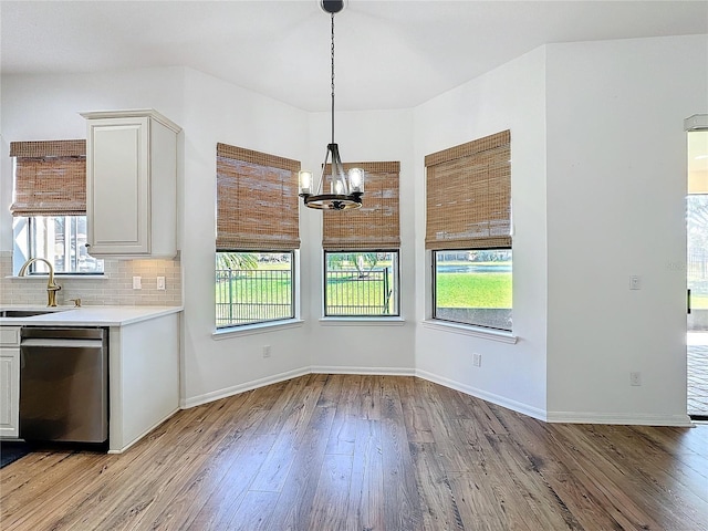 unfurnished dining area featuring sink, a notable chandelier, and light hardwood / wood-style flooring