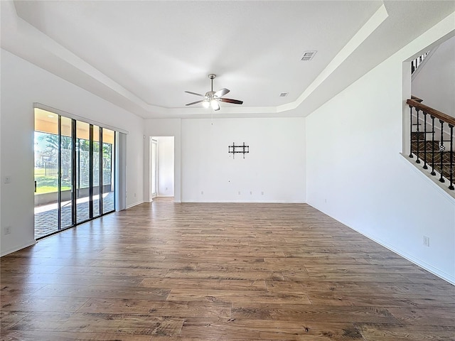 unfurnished room with dark hardwood / wood-style flooring, a raised ceiling, and ceiling fan