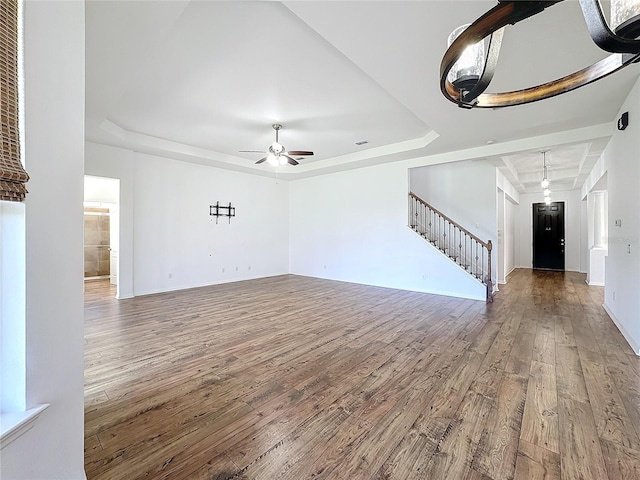 unfurnished living room featuring wood-type flooring, ceiling fan, and a tray ceiling