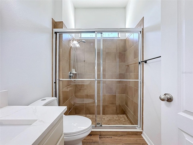 bathroom featuring vanity, hardwood / wood-style floors, walk in shower, and toilet