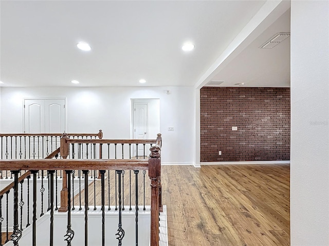 corridor with hardwood / wood-style flooring and brick wall