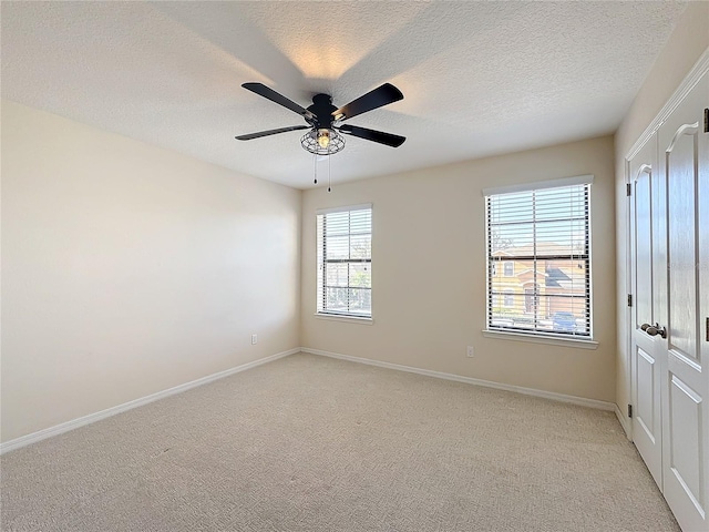 empty room with light carpet, a textured ceiling, and ceiling fan