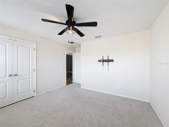 unfurnished bedroom with carpet, a textured ceiling, and a closet