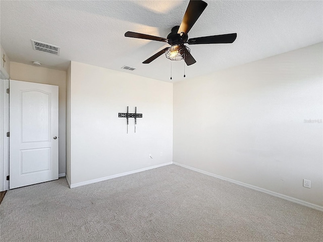 empty room with ceiling fan, light carpet, and a textured ceiling