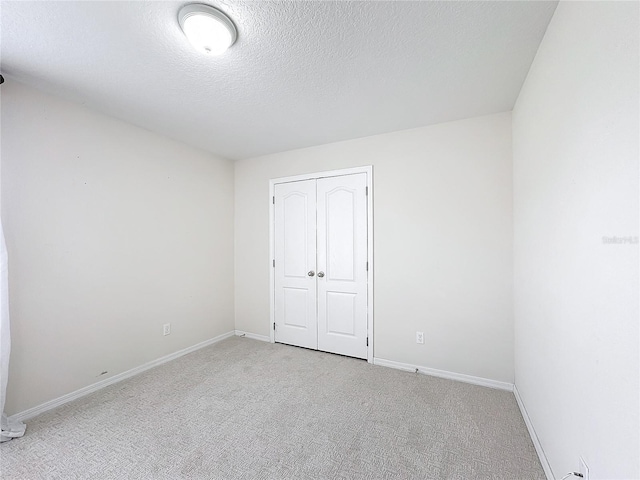 unfurnished bedroom featuring light colored carpet, a closet, and a textured ceiling