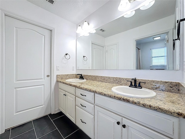 bathroom featuring tile patterned flooring, vanity, and a textured ceiling