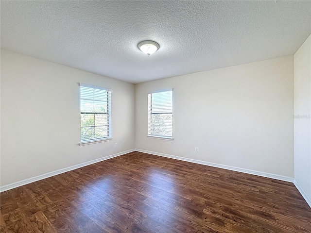 spare room featuring dark wood-type flooring and a textured ceiling