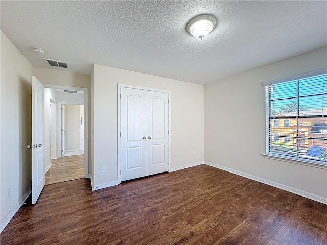 unfurnished bedroom featuring dark hardwood / wood-style floors, a closet, and a textured ceiling