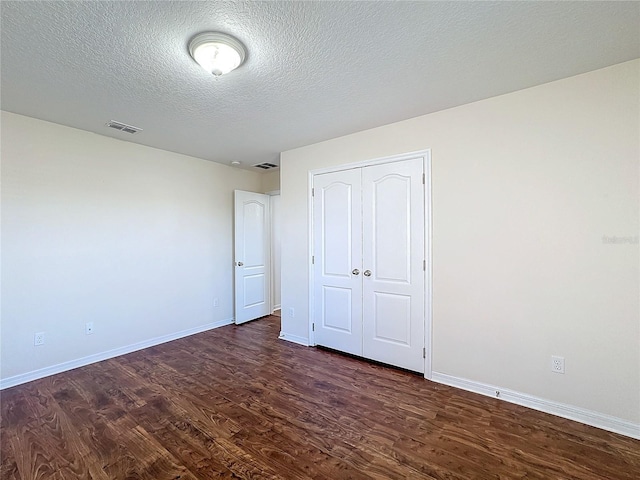 unfurnished bedroom with dark wood-type flooring, a closet, and a textured ceiling