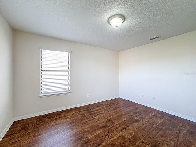 unfurnished room with a textured ceiling and dark hardwood / wood-style flooring