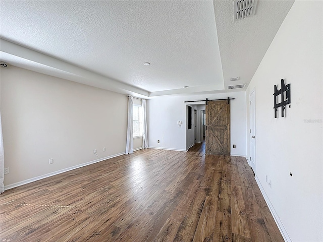 unfurnished room with hardwood / wood-style flooring, a barn door, and a textured ceiling