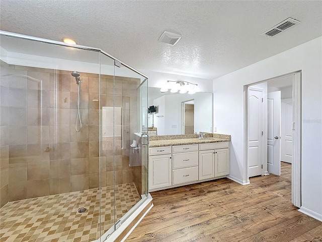 bathroom featuring wood-type flooring, an enclosed shower, vanity, and a textured ceiling