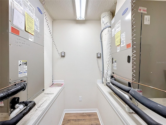 clothes washing area featuring heating unit and hardwood / wood-style flooring