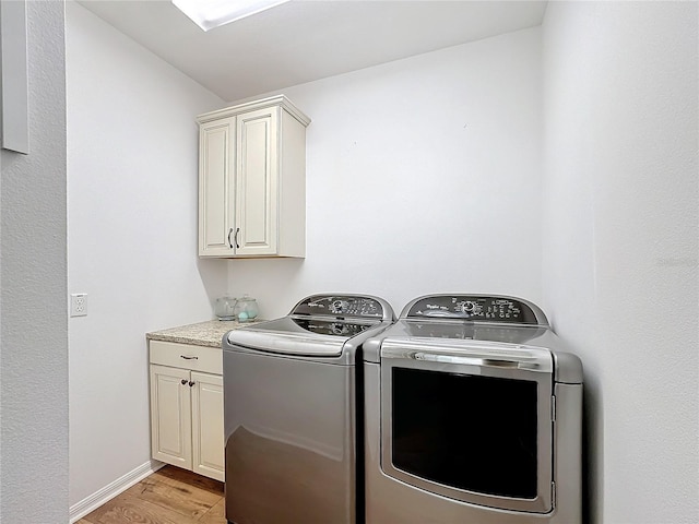 laundry area featuring cabinets, light hardwood / wood-style floors, and independent washer and dryer