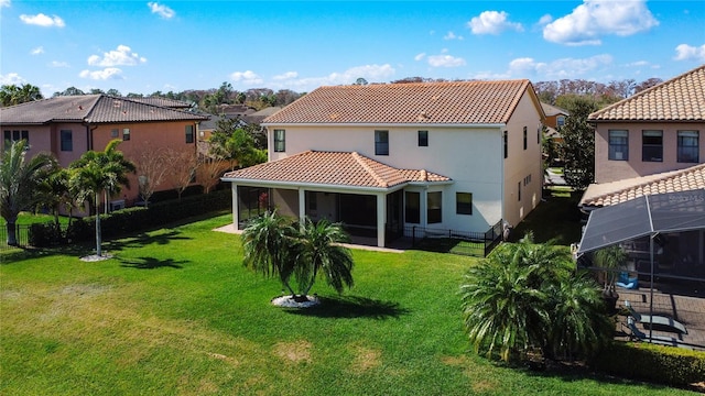 back of property featuring a sunroom, glass enclosure, and a lawn