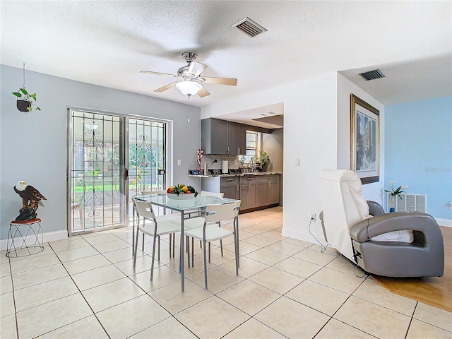 tiled dining space with a textured ceiling, a wealth of natural light, and ceiling fan