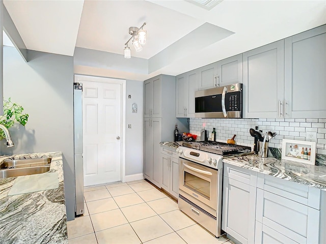 kitchen featuring sink, backsplash, stainless steel appliances, and light stone countertops