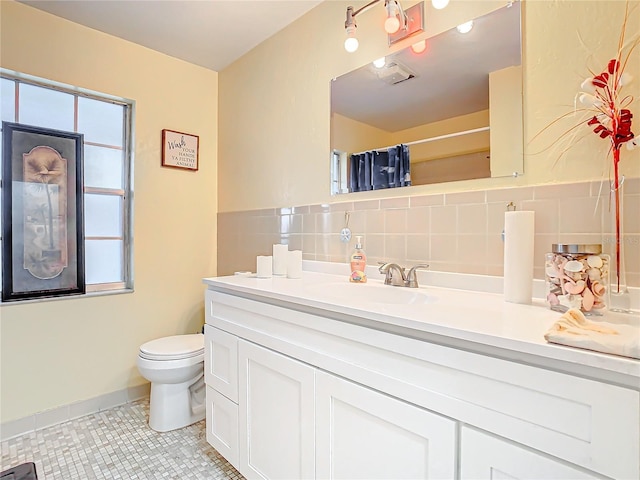 bathroom featuring curtained shower, tile walls, tile patterned flooring, vanity, and toilet