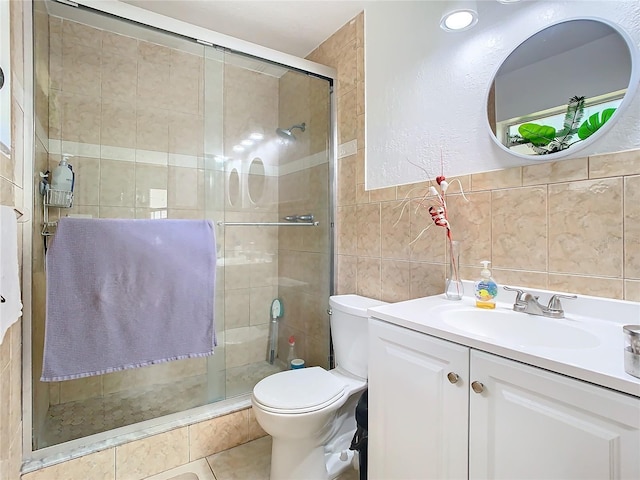 bathroom featuring tile patterned floors, toilet, an enclosed shower, tile walls, and vanity