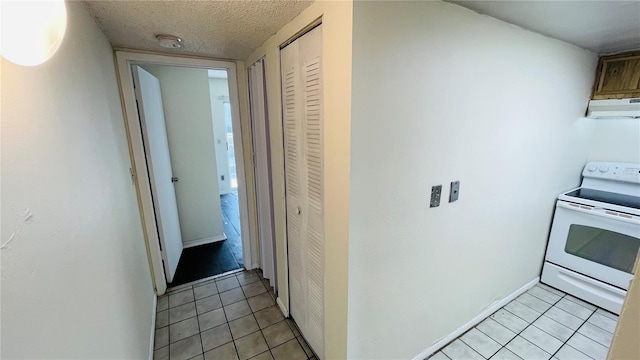 hallway with a textured ceiling and light tile patterned floors