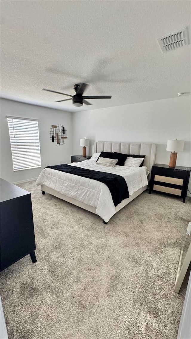 bedroom featuring ceiling fan, carpet flooring, and a textured ceiling