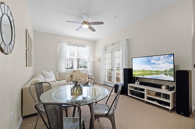 dining space with ceiling fan and light colored carpet