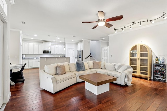 living room with dark wood-type flooring, rail lighting, ceiling fan, wine cooler, and ornamental molding