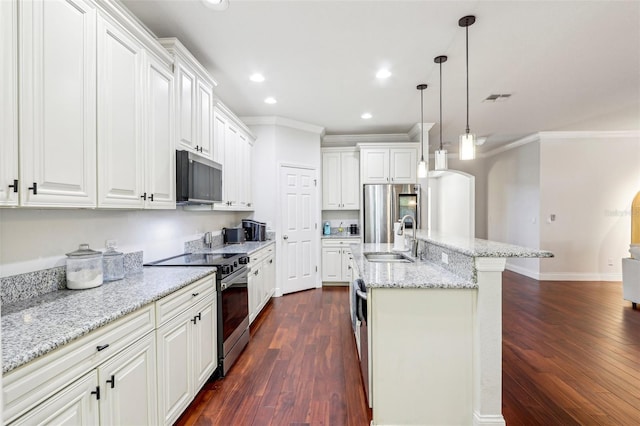 kitchen with appliances with stainless steel finishes, sink, white cabinets, hanging light fixtures, and a kitchen island with sink