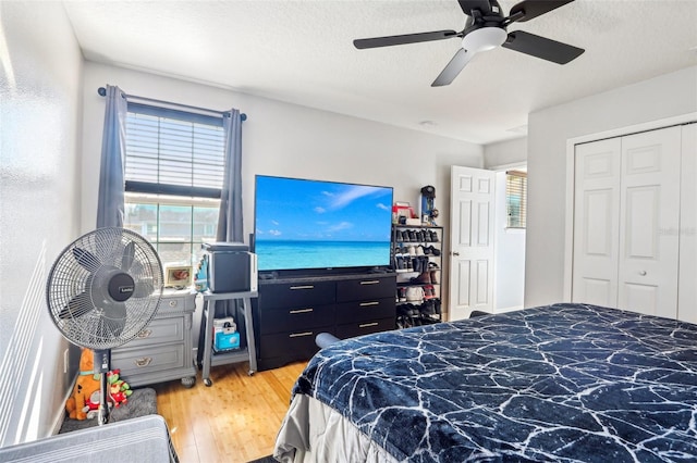 bedroom featuring wood-type flooring, ceiling fan, a textured ceiling, and a closet