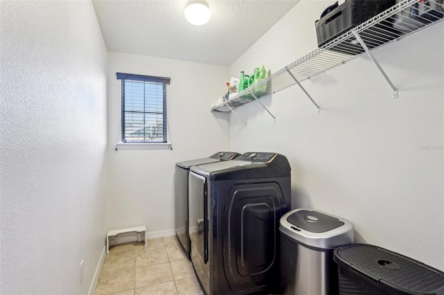 clothes washing area with light tile patterned flooring, washer and clothes dryer, and a textured ceiling