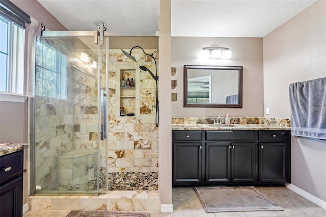 bathroom with vanity, a textured ceiling, and a tile shower