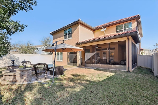 back of property featuring ceiling fan, a patio area, a sunroom, and a lawn