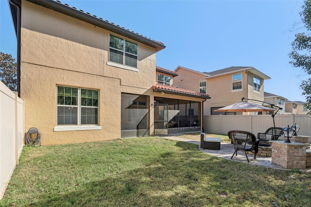 back of house with a patio, a sunroom, a lawn, and an outdoor fire pit