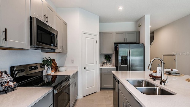 kitchen with light tile patterned flooring, stainless steel appliances, gray cabinets, and sink