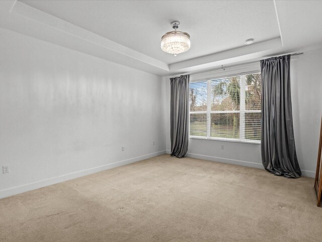 1431 Milledge Ln, Davenport, FL 33896 - empty room featuring light carpet, a notable chandelier, and a raised ceiling
