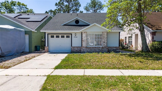 view of front facade with roof with shingles, driveway, a front yard, brick siding, and a garage