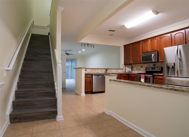 kitchen with stainless steel appliances, crown molding, backsplash, light tile patterned floors, and kitchen peninsula