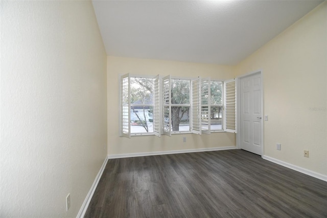 empty room featuring dark wood-type flooring and vaulted ceiling